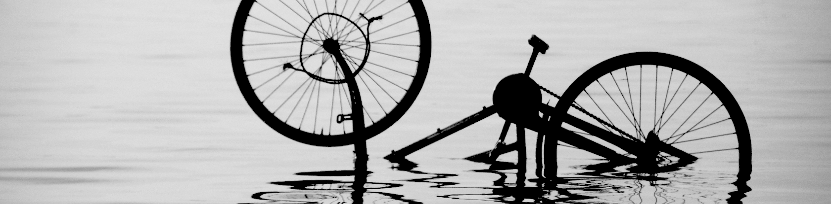 Black and white photograph of a bicycle partly submerged in water